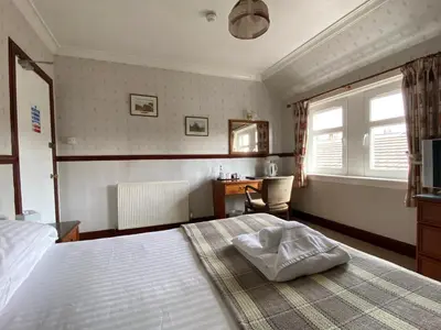 a bedroom with a bed and a desk and window at Kings Arms Hotel in Lockerbie