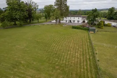 a large field of grass with a house in the background at Dryfesdale Hotel - BW Signature Collection in Lockerbie