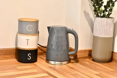 a coffee maker and two vases on a wooden floor at *Penthouse Luxury Apartment 2min to City in Carlisle