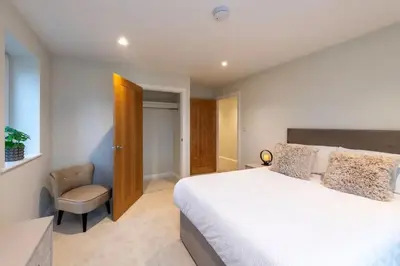 a bedroom with a large white bed and a chair at *Luxury Apartment 2min from City in Carlisle