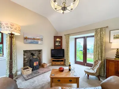 a living room with a fireplace and a tv at The Clachan Bothy in Drumpark