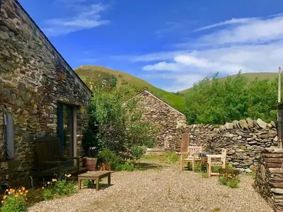 a stone house with benches and a stone wall at 1 Bed in Watermillock 94065 in Watermillock