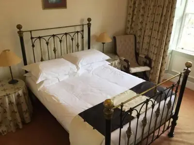 a bedroom with a large bed and a chair at Kirkconnel Hall Hotel in Lockerbie