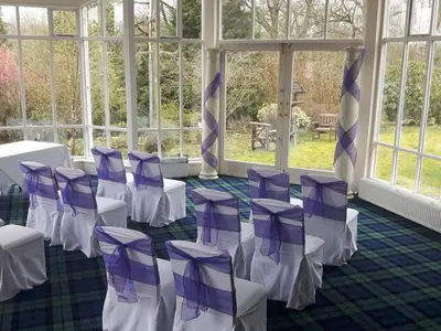 a room with purple and white chairs and windows at Kirkconnel Hall Hotel in Lockerbie