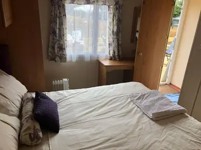 a bedroom with a white bed with a window at 2 bedroom static caravan in Muirkirk