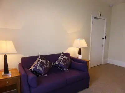 a living room with a purple couch and two lamps at Bailey Ground Lodge in Seascale
