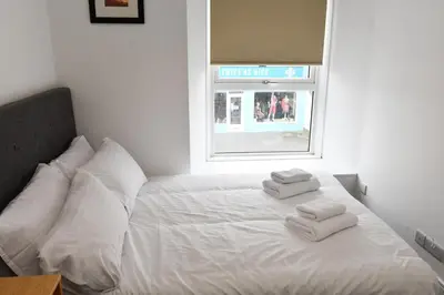 a white bed with two towels on top of it at Troon Portland Apt A in Troon