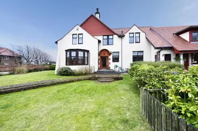 a large white house with a grass yard at Dunvegan Apartment Troon in Troon