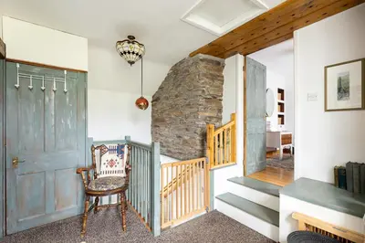 a room with a staircase and a door and a chair at HIGH TREES BYRE - Two bed Cottage with Log Burner & Incredible Views in Workington