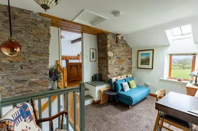 a living room with a blue couch and a stone wall at HIGH TREES BYRE - Two bed Cottage with Log Burner & Incredible Views in Workington