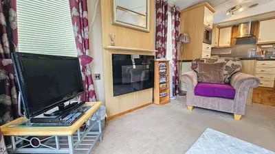 a living room with a flat screen tv and a chair at Foxgloves and Ivy in Cockermouth