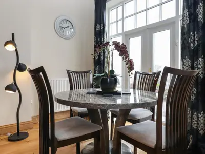 a dining room with a table and chairs and a clock at 5 Ladstock Hall in Keswick