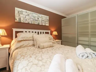 a bedroom with a large white bed with two lamps at 5 Ladstock Hall in Keswick