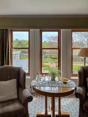 a living room with two chairs and a table and windows at Lochgreen House Hotel & Spa in Loans