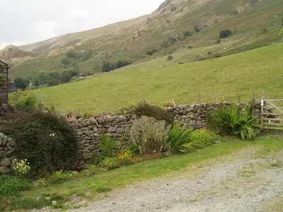a stone wall next to a grassy hill at Fisher-gill Camping Barn in Thirlmere