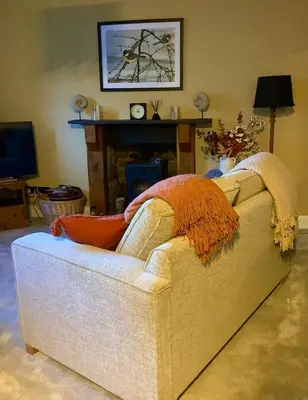 a couch with a blanket on it in a living room at Holmlea Cottage in Moffat