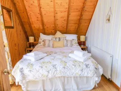 a white bed in a room with a wooden ceiling at Thistle Dubh 