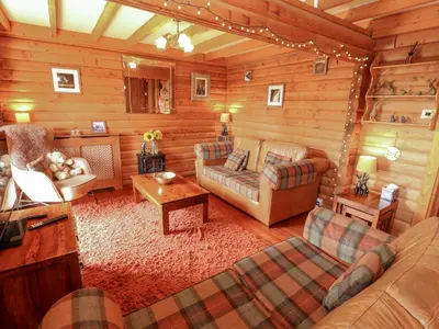 a living room with furniture in a log cabin at Thistle Dubh 