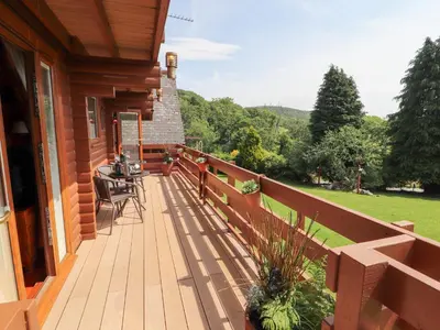 a wooden deck with a table and chairs on a house at Thistle Dubh 