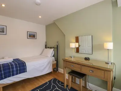a bedroom with a bed and a desk with a mirror at Baystones in Keswick