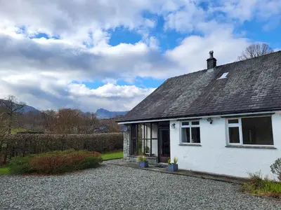 a white house with a roof on a gravel driveway at Beckfoot Chapel Stile - Ambleside in Chapel Stile
