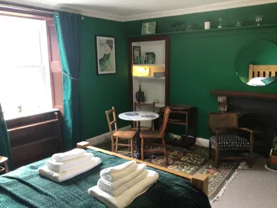 a green bedroom with a bed and a table and chairs at Mansefield Rooms in Lockerbie