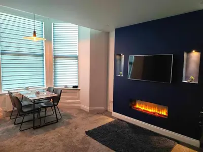 a living room with a table and a fireplace at Antrim Holiday Apartment in Ramsey