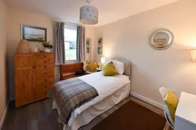a bedroom with a bed and a dresser at Ladyland Cottage in Maybole in Maybole