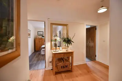 a room with a table with a basket and a hallway at Ladyland Cottage in Maybole in Maybole