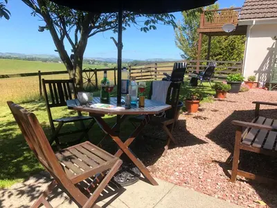 a wooden table and chairs under an umbrella at Southpark House in Dumfries