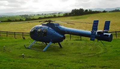 a blue helicopter sitting on a field of grass at Southpark House in Dumfries