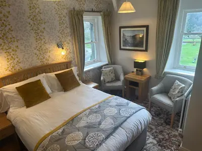 a bedroom with a bed and a chair and windows at Burleigh Mead in Keswick