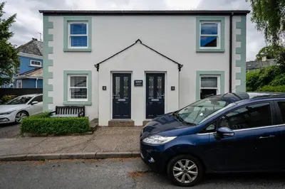 a blue car parked in front of a white house at Acorn Apartment 2 (upper) in Keswick