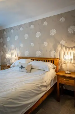 a bedroom with a large bed with snowflake wallpaper at Acorn Apartment 2 (upper) in Keswick