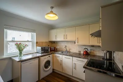 a kitchen with white cabinets and a washer and dryer at Acorn Apartment 2 (upper) in Keswick