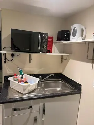 a kitchen counter with a sink and a microwave at Doddick Bothy in Threlkeld