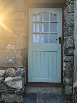 a garage door with a window on a stone wall at Doddick Bothy in Threlkeld