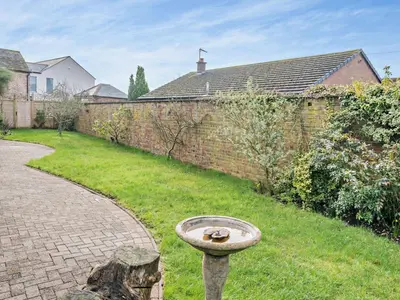 a birdbath in a yard next to a brick wall at 4 Bed in Crosby-on-Eden 94398 in Crosby