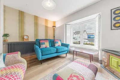 a living room with a blue couch and a window at Blue Sky Cottage in Keswick