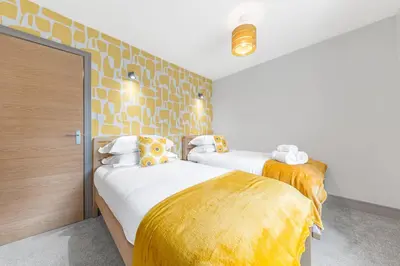 two beds in a room with yellow and white at Blue Sky Cottage in Keswick