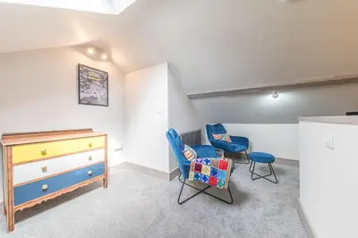 a bedroom with two blue chairs and a dresser at Blue Sky Cottage in Keswick