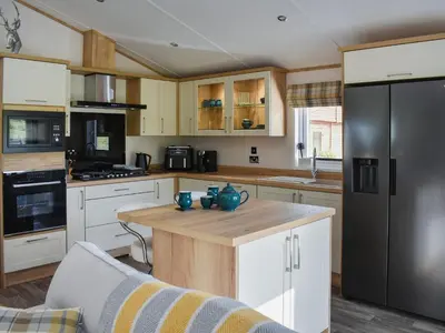 a kitchen with white cabinets and a black refrigerator at Beaumont Lodge in Plumbland