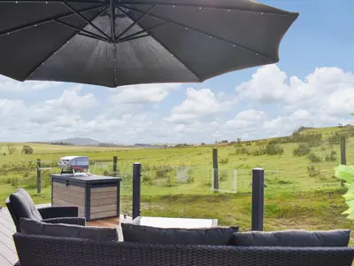 a patio with chairs and an umbrella and a grill at Beaumont Lodge in Plumbland