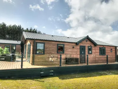 a log cabin with a deck and a house at Beaumont Lodge in Plumbland