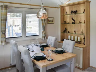 a dining room with a wooden table and chairs at Beaumont Lodge in Plumbland