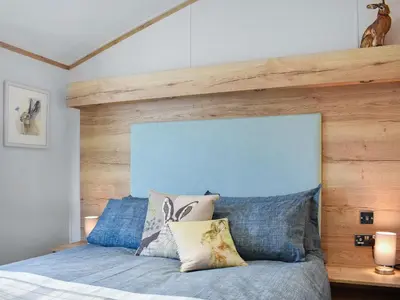 a bedroom with a bed with a wooden headboard at Beaumont Lodge in Plumbland