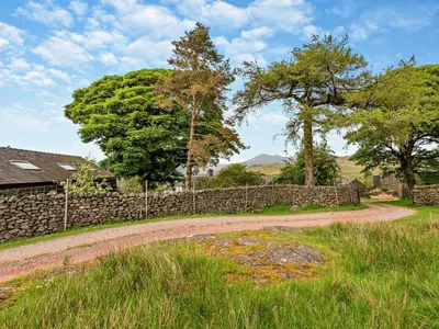 a dirt road next to a stone wall and trees at 1 Bed in Eskdale 94530 in Eskdale