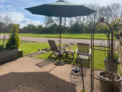 a patio with two chairs and a table with an umbrella at Pippa's Cottage - Uk42332 in Little Blencow