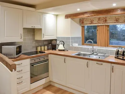a kitchen with white cabinets and a sink at Pippa's Cottage - Uk42332 in Little Blencow