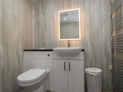 a bathroom with a toilet and a sink and a mirror at The Gardener's Bothy in Penrith